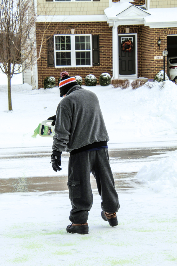 Man pouring Revital-Ice Ice Melt on his snowy driveway
