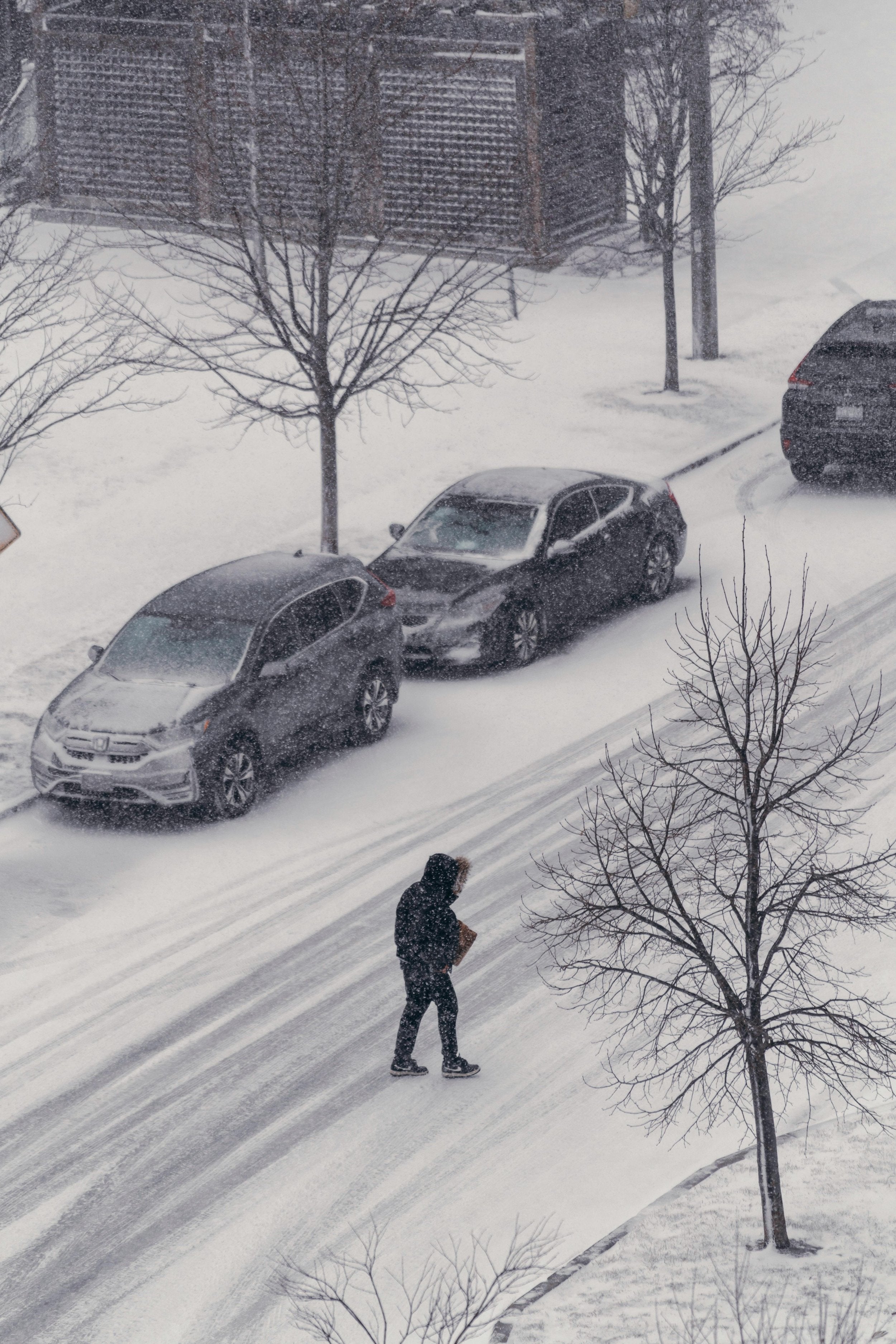 A man walking down a snowy road in a snowstorm